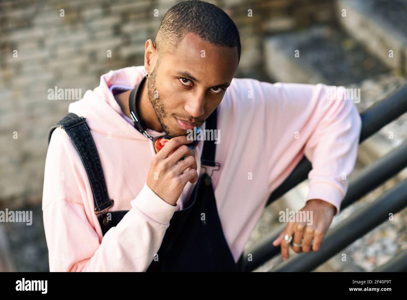 Giovane uomo nero di indossare un abbigliamento informale sulle fasi di URBAN. Grave ragazzo africano con bib pants all'aperto Foto Stock