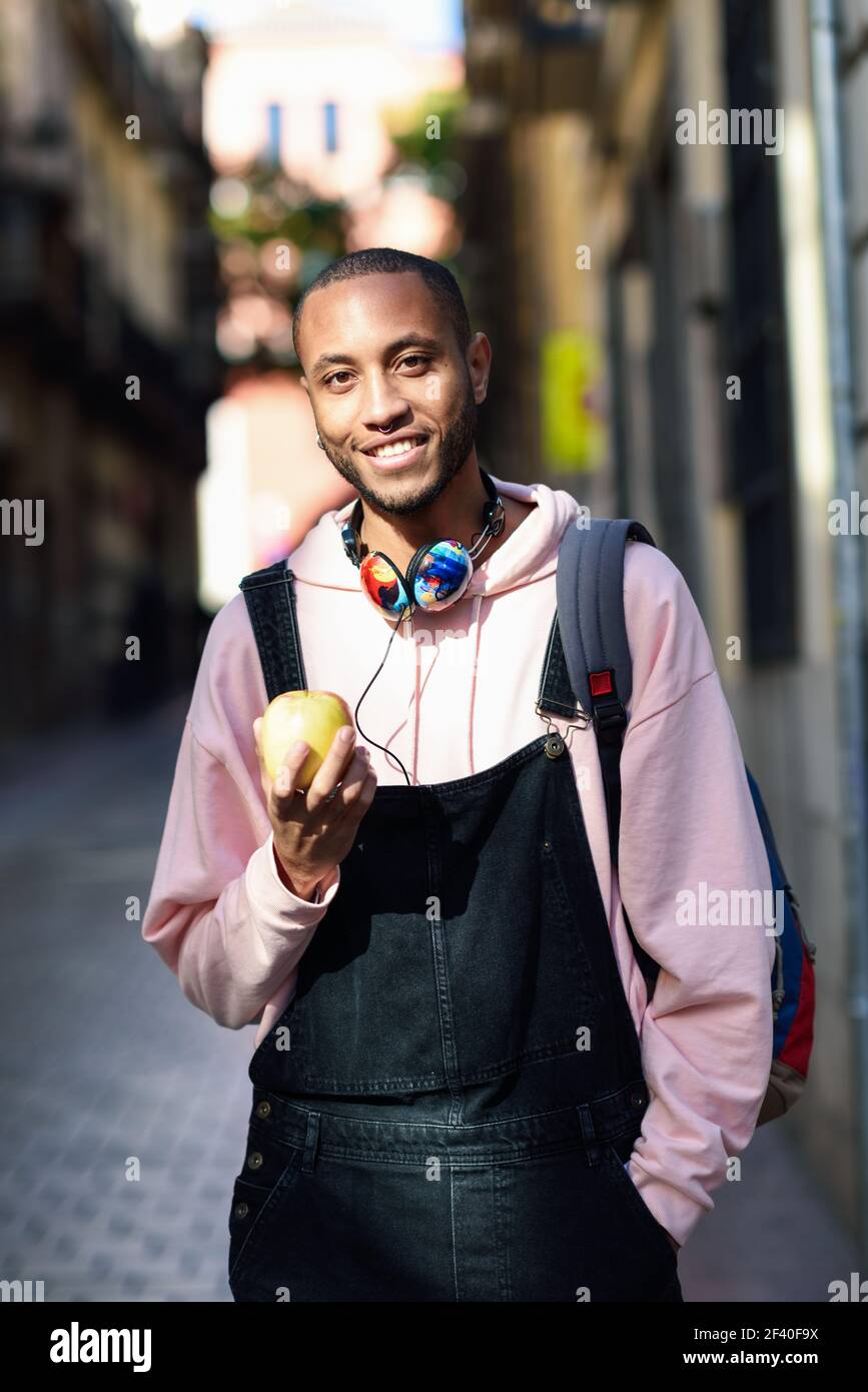 Giovane uomo nero una mela a piedi giù per la strada. Il concetto di stile di vita. Foto Stock