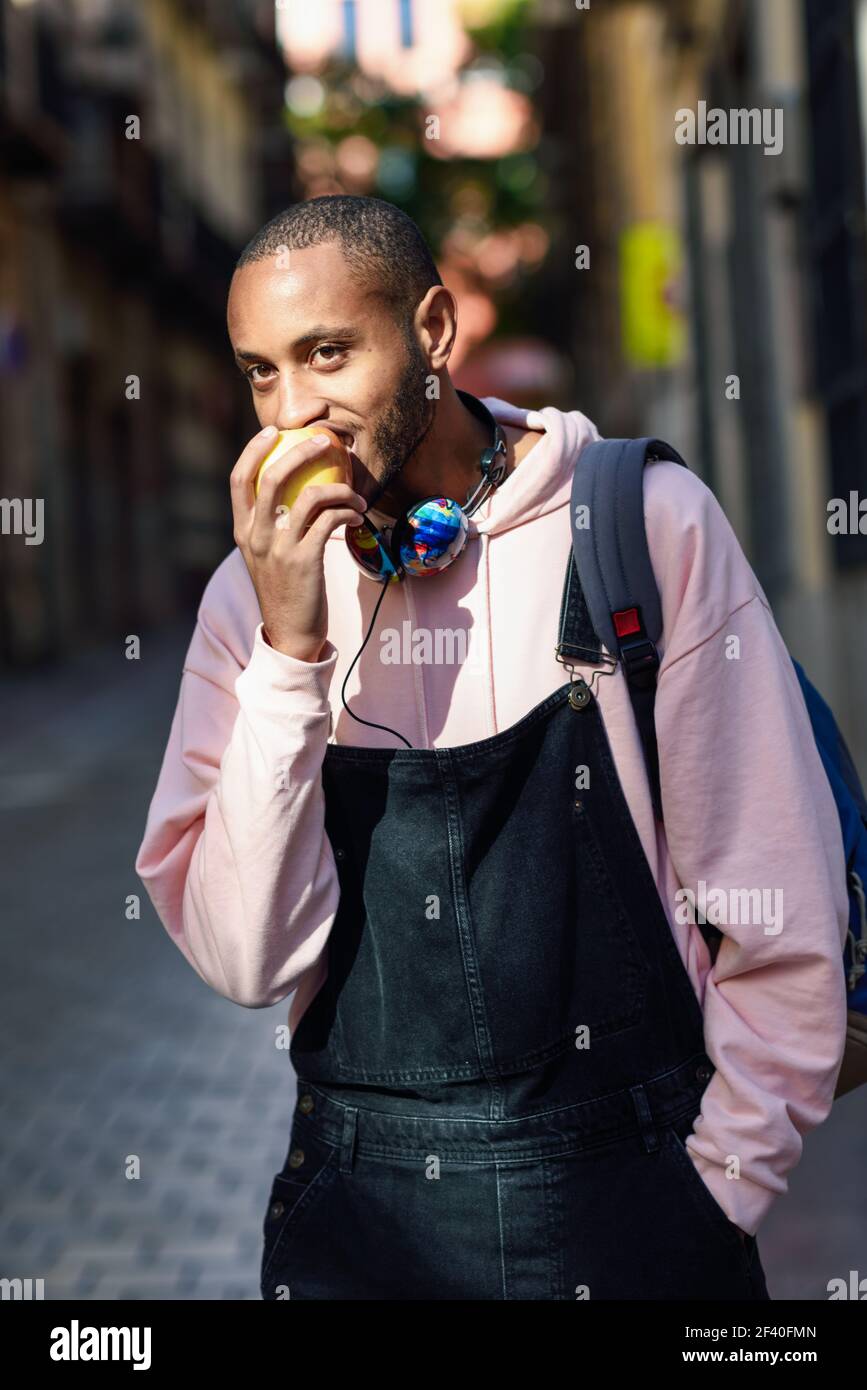 Giovane uomo nero una mela a piedi giù per la strada. Il concetto di stile di vita. Foto Stock