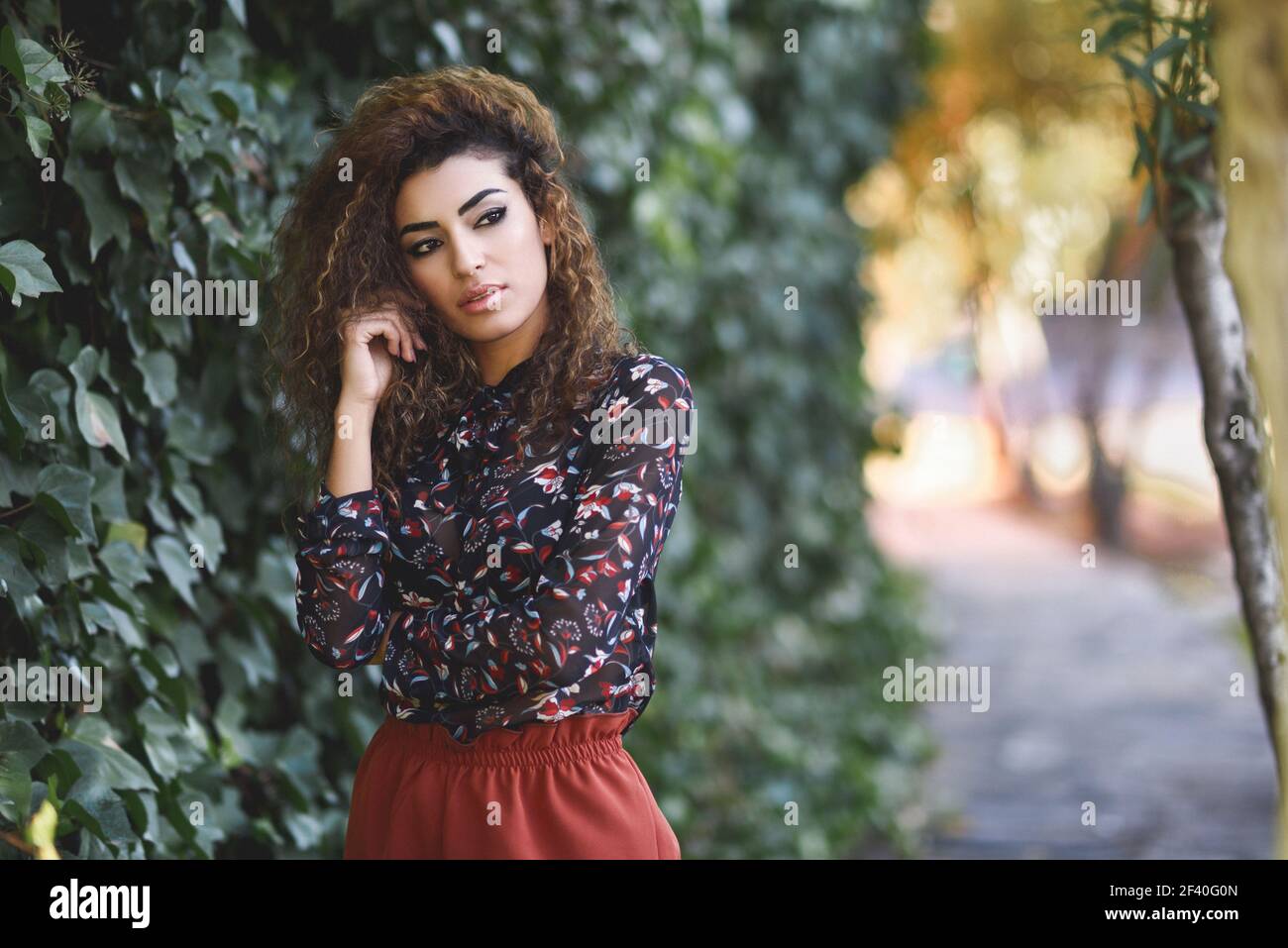 Bellissima giovane donna araba con nero capelli ricci. Ragazza araba di indossare abiti casual in strada. Foto Stock