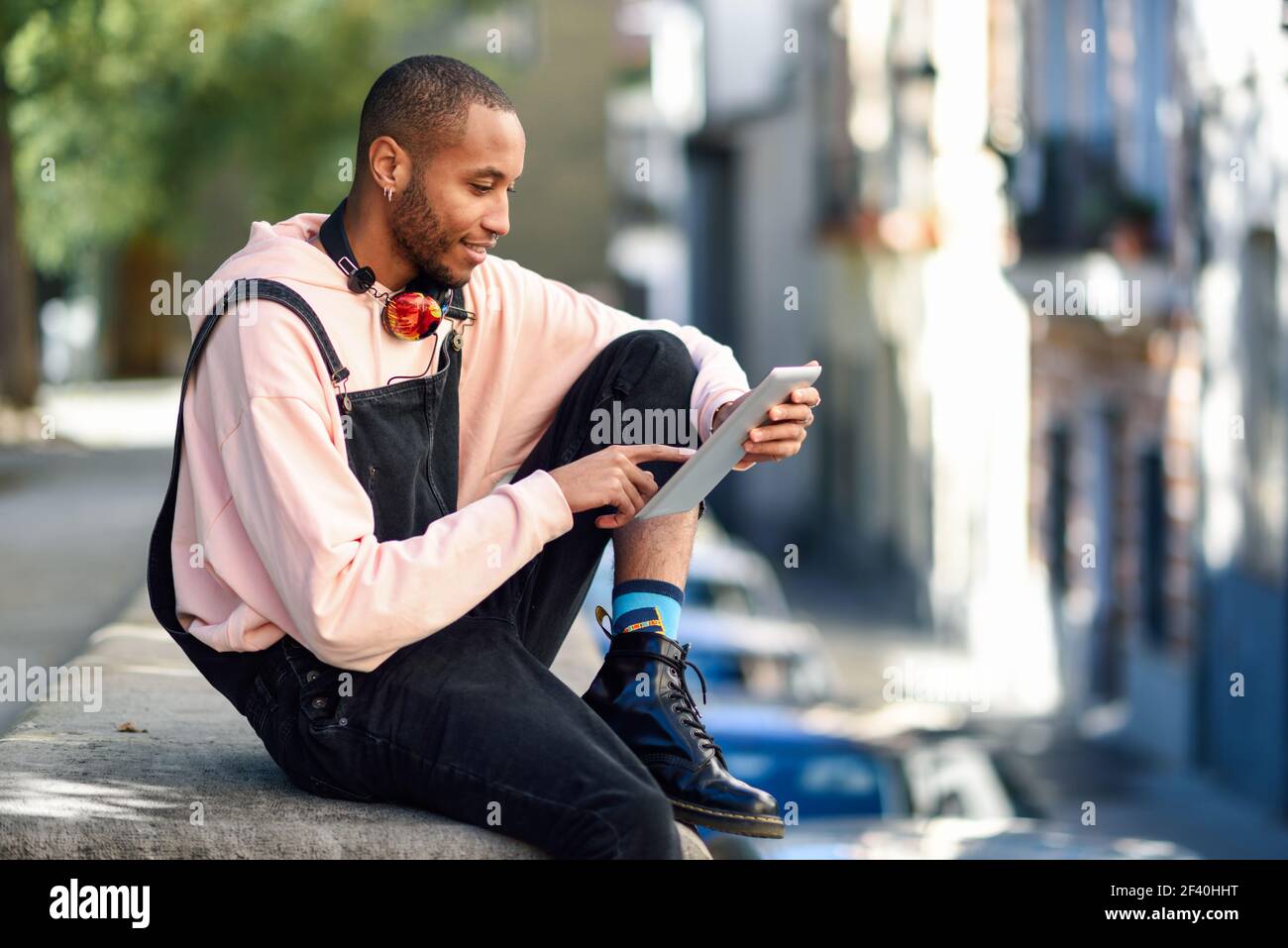 Giovane uomo nero che usa il tablet digitale in ambiente urbano. Concetti di stile di vita e tecnologia. Giovane uomo nero che usa il tablet digitale in ambiente urbano. Foto Stock