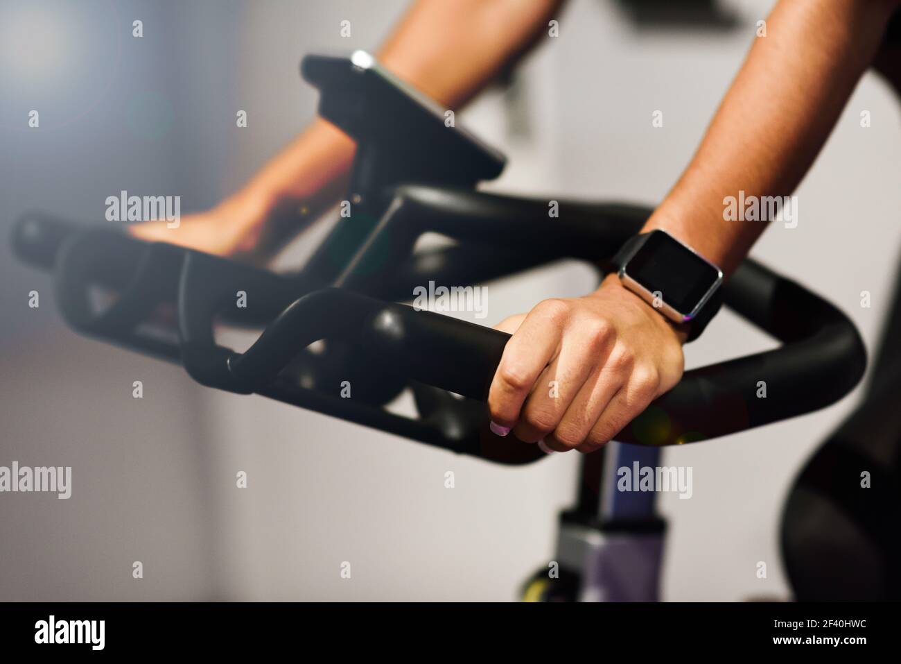Mani di una donna che si allenano in palestra facendo filatura o ciclo indoor con orologio intelligente. Concetto di sport e fitness. Foto Stock