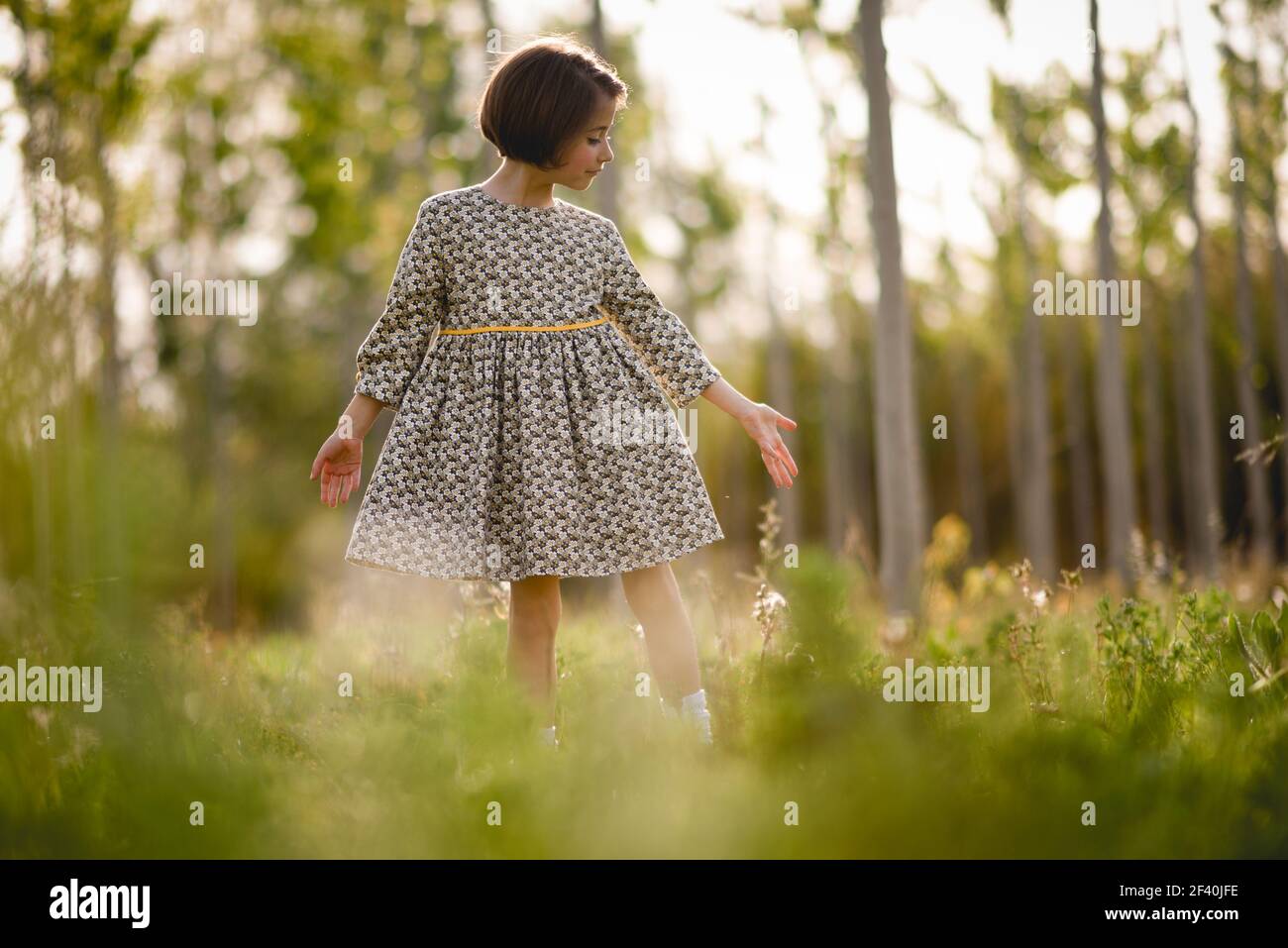 Bambina che cammina nel campo della natura indossando un bel vestito. Bambina in campo natura che indossa un bel vestito Foto Stock