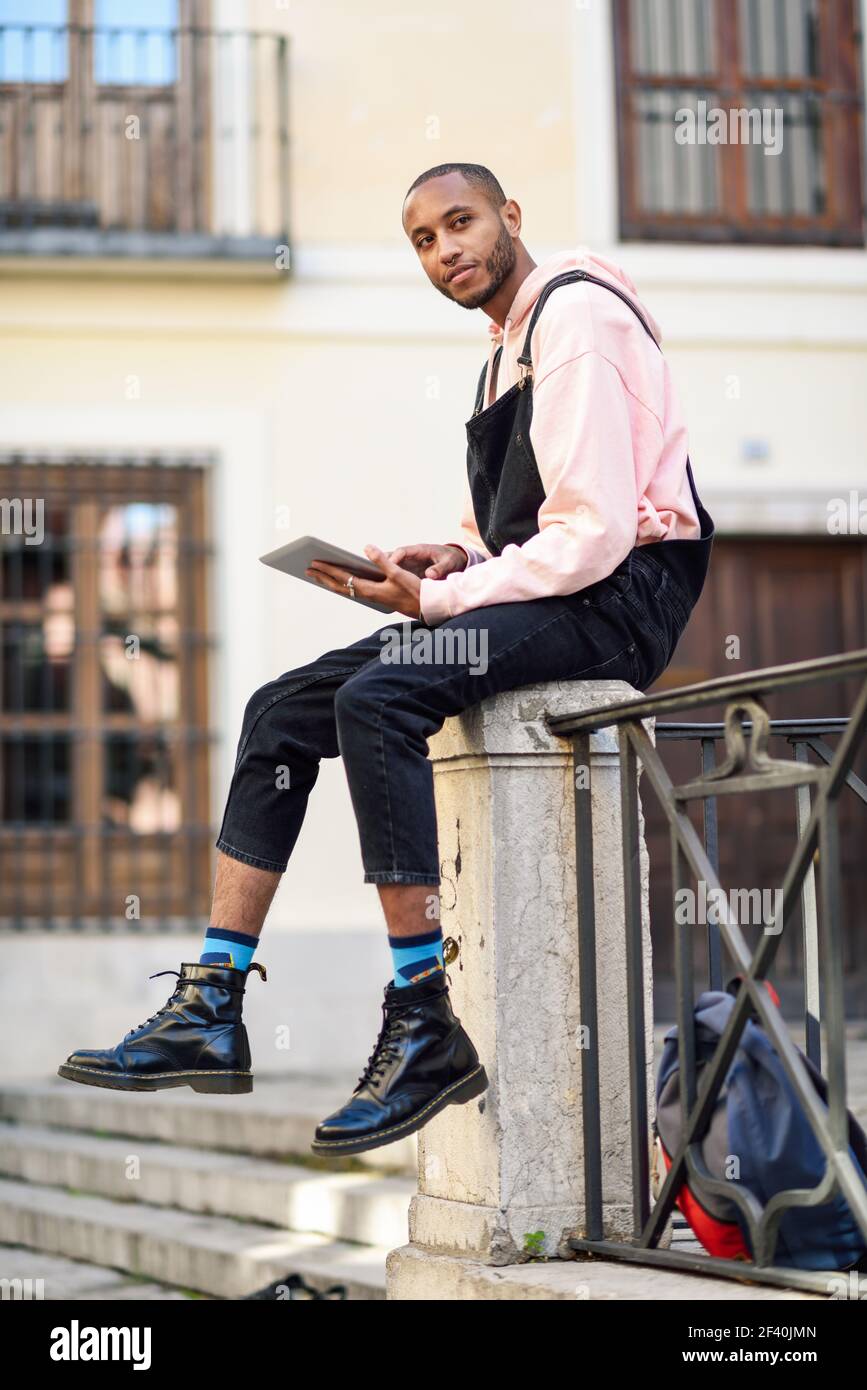 Giovane uomo nero che usa il tablet digitale in ambiente urbano. Concetti di stile di vita e tecnologia. Giovane uomo nero che usa il tablet digitale in ambiente urbano. Foto Stock