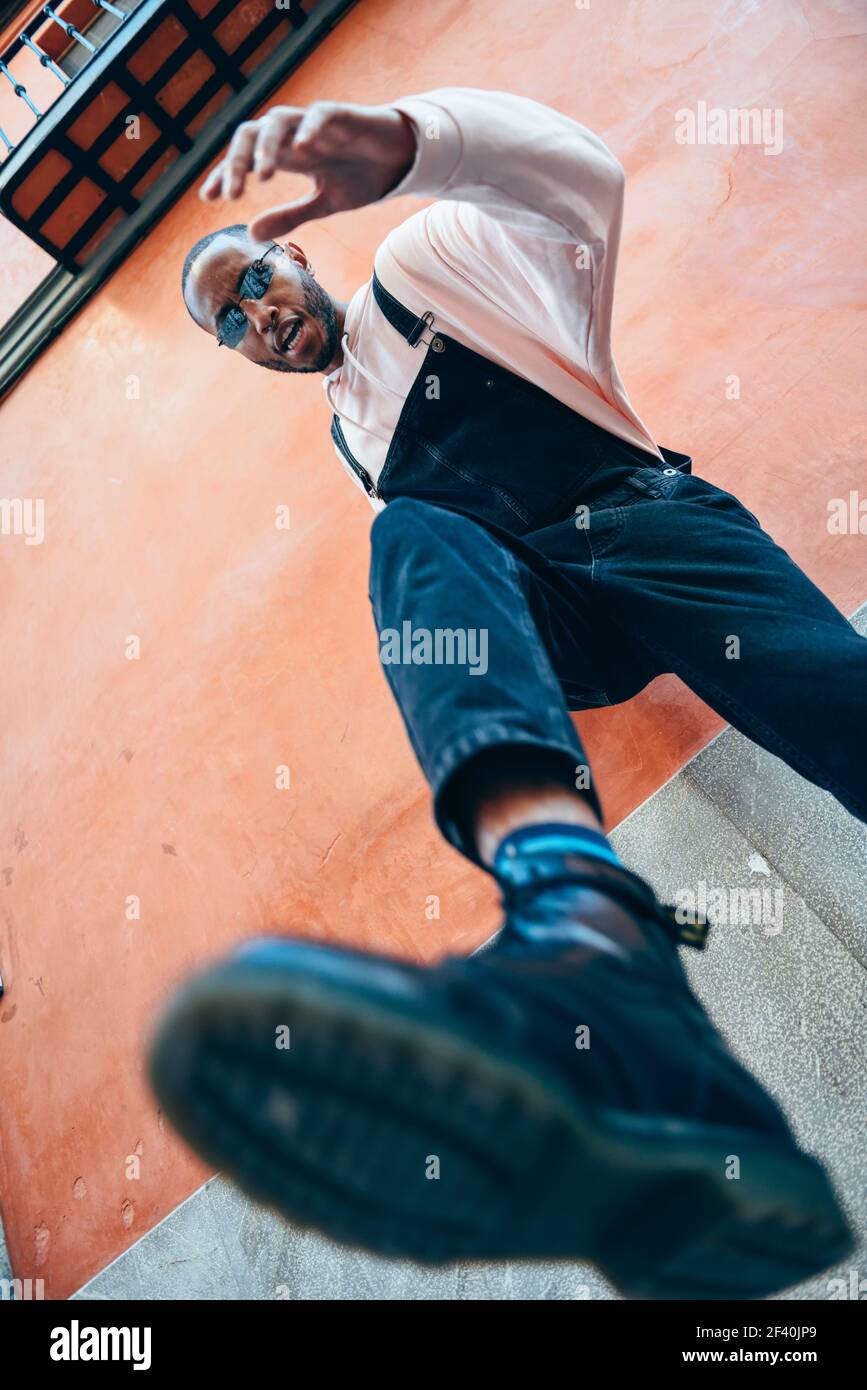 Giovane uomo nero che calcia verso terra. Concetto di stile di vita.. Giovane uomo nero che calcia verso terra. Foto Stock