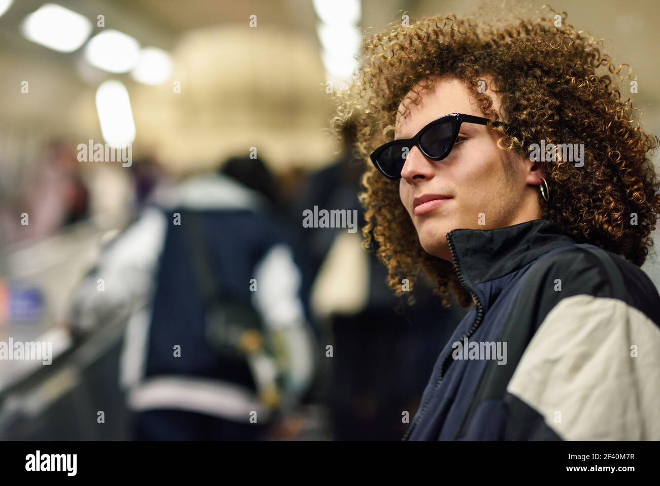 Giovane uomo con capelli ricci che salirà al piano di una stazione della metropolitana. Giovane uomo che salirà al piano di sopra di una stazione della metropolitana. Foto Stock