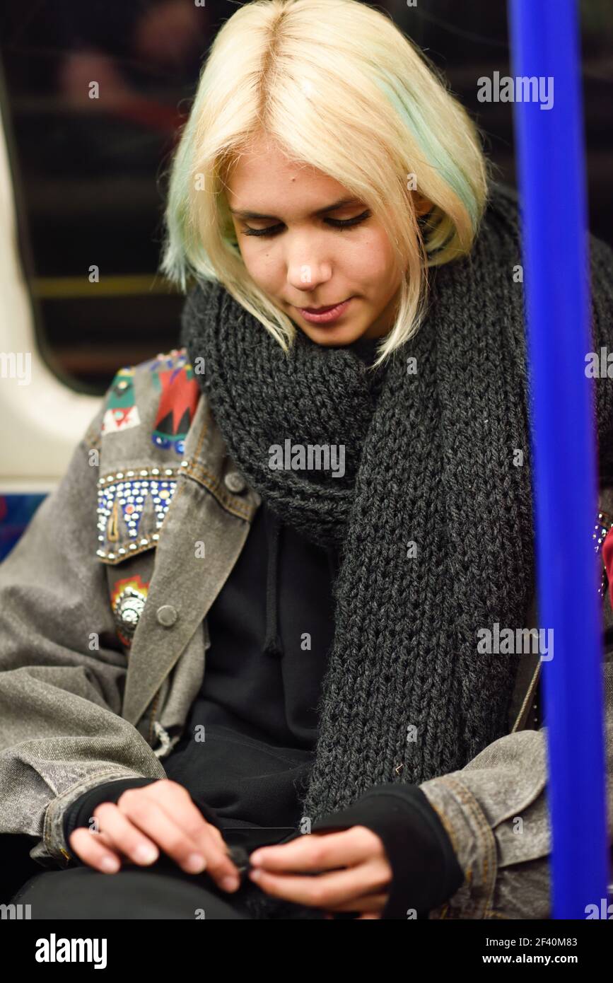 Giovane donna con capelli corti seduta all'interno del carro sotterraneo a Londra. Giovane donna con capelli corti seduta all'interno del carro sotterraneo Foto Stock