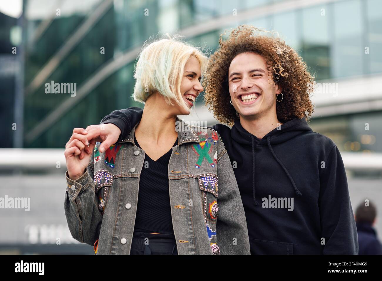 Felice coppia ridendo in ambiente urbano. Giovane donna e uomo che si godono l'un l'altro.. Felice giovane coppia ridendo in ambiente urbano Foto Stock