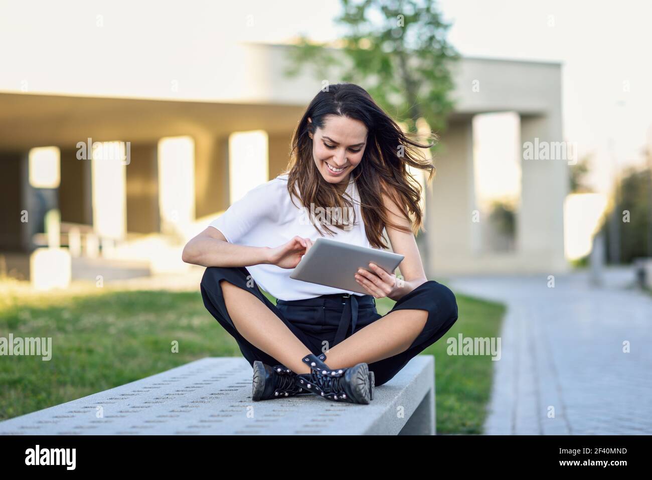 Donna di mezza età che usa un tablet digitale seduto all'aperto in ambiente urbano. Giovane donna che usa un tablet digitale seduto all'aperto in ambiente urbano. Foto Stock