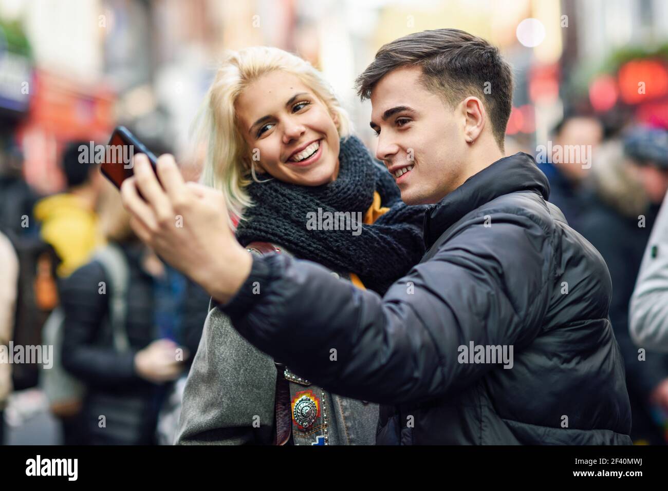 Felice coppia di turisti che prendono selfie in una strada affollata di Londra. Felice coppia di turisti che prendono selfie in una strada affollata. Foto Stock