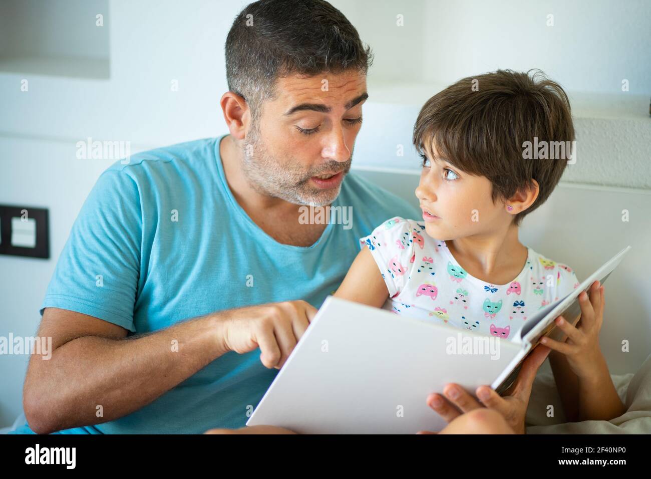 Il papà divertente e la bambina adorabile si divertono sul letto. Padre di mezza età con la sua figlia di otto anni che usa un tablet digitale in camera da letto. Padre di mezza età con la figlia di otto anni che usa un tablet digitale in camera da letto. Foto Stock