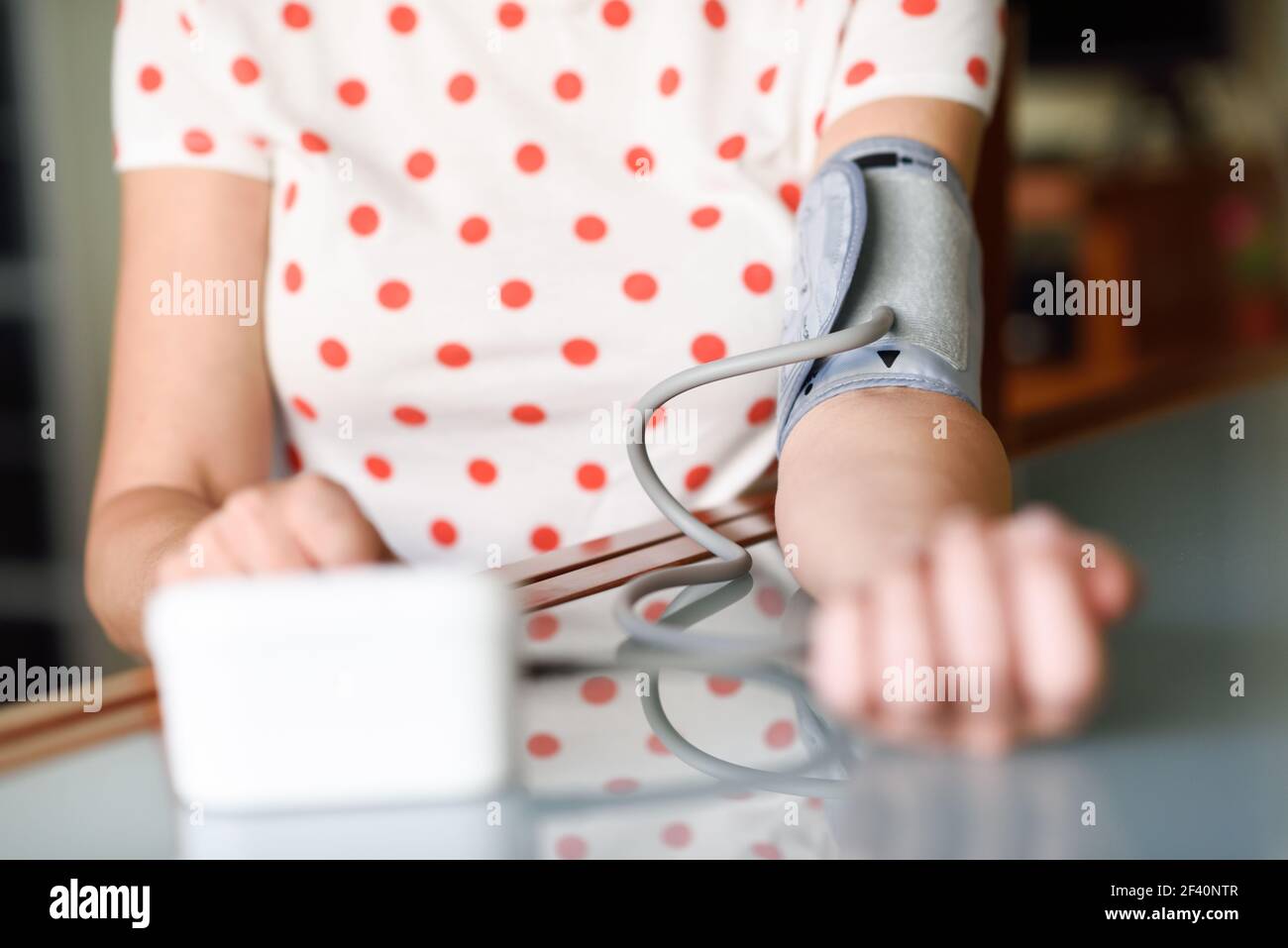 Donna di mezza età che misura la propria pressione sanguigna con un dispositivo elettronico per la misurazione della pressione sanguigna a casa. Donna che misura la propria pressione sanguigna a casa. Foto Stock