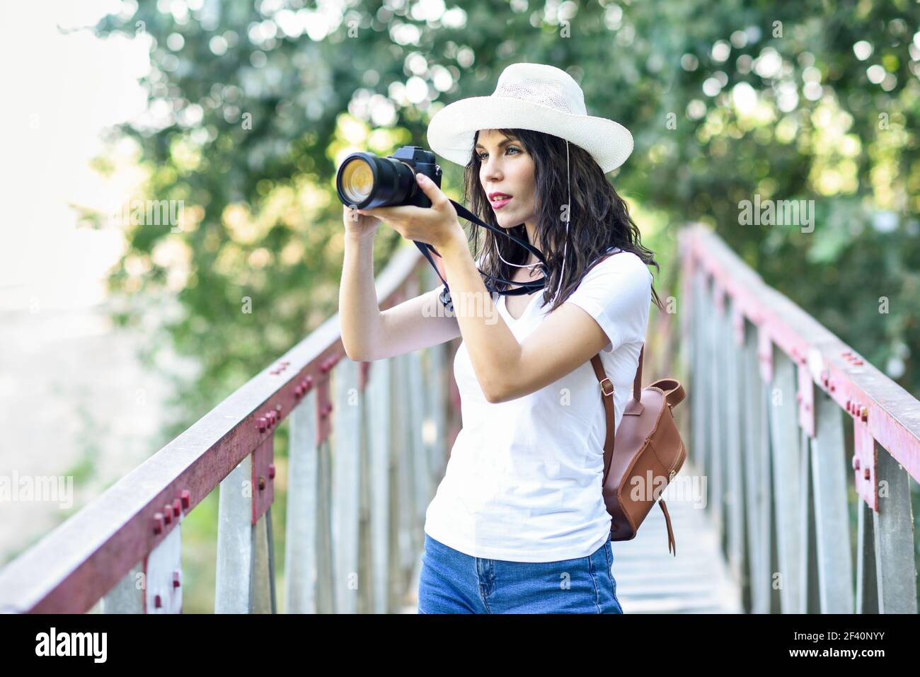 Bella escursionista giovane donna scattando fotografie con una macchina fotografica mirrorless, indossando cappello di paglia, escursioni in campagna. Donna escursionista che scatta fotografie con una fotocamera mirrorless Foto Stock