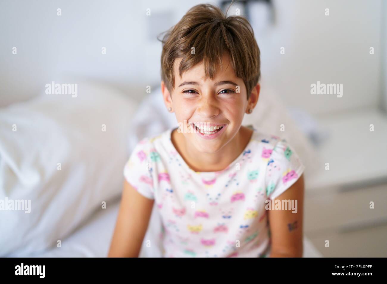 Felice bambina, di otto anni, seduta sul suo letto a casa ridendo. Bambina, di otto anni, sdraiata sul suo letto Foto Stock