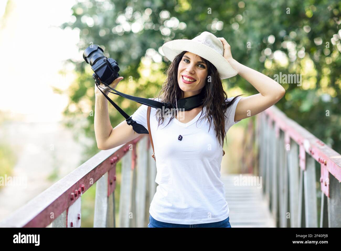 Bella escursionista giovane donna scattando fotografie con una macchina fotografica mirrorless, indossando cappello di paglia, escursioni in campagna. Donna escursionista che scatta fotografie con una fotocamera mirrorless Foto Stock