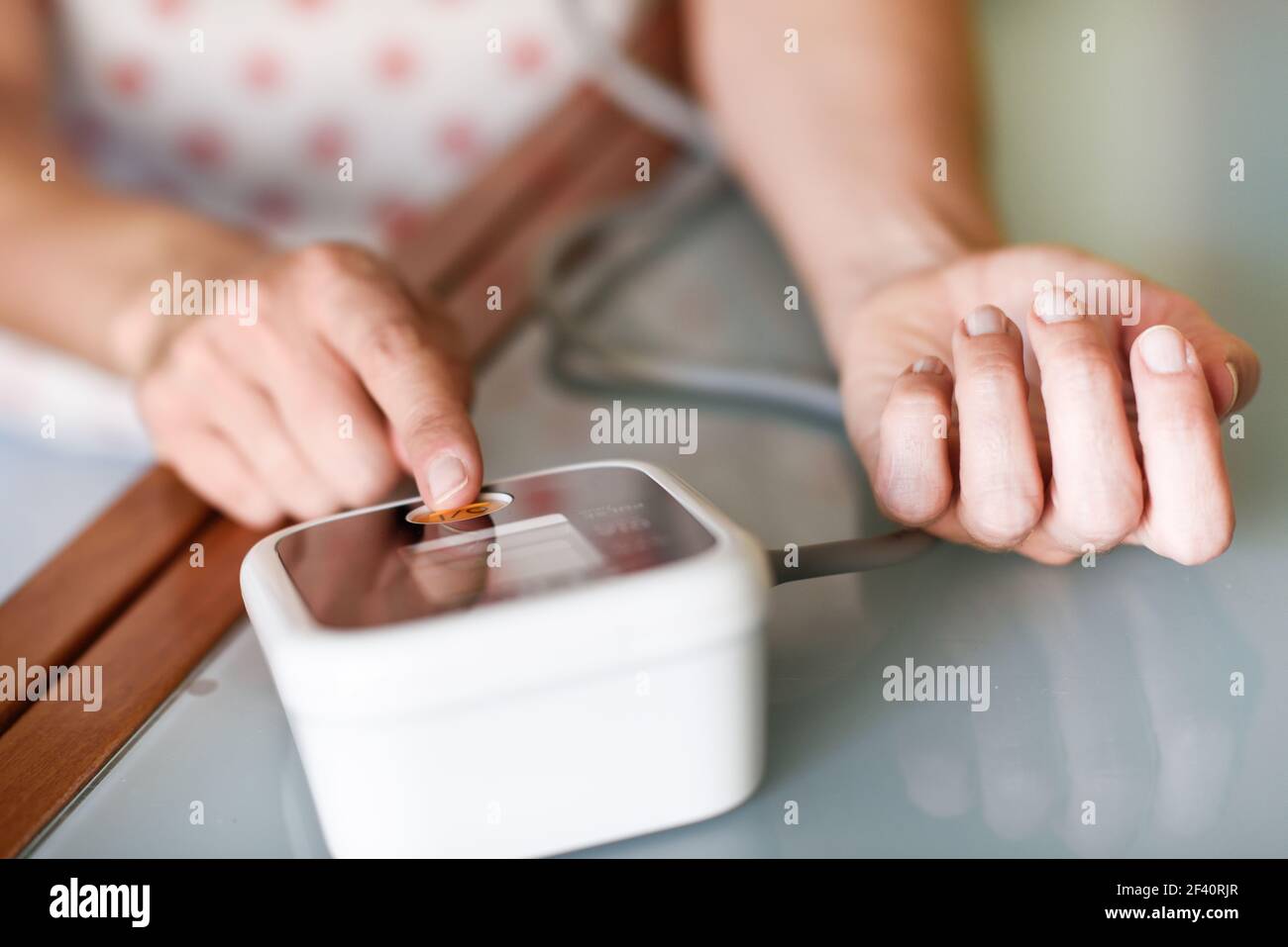 Donna di mezza età che misura la propria pressione sanguigna con un dispositivo elettronico per la misurazione della pressione sanguigna a casa. Donna che misura la propria pressione sanguigna a casa. Foto Stock