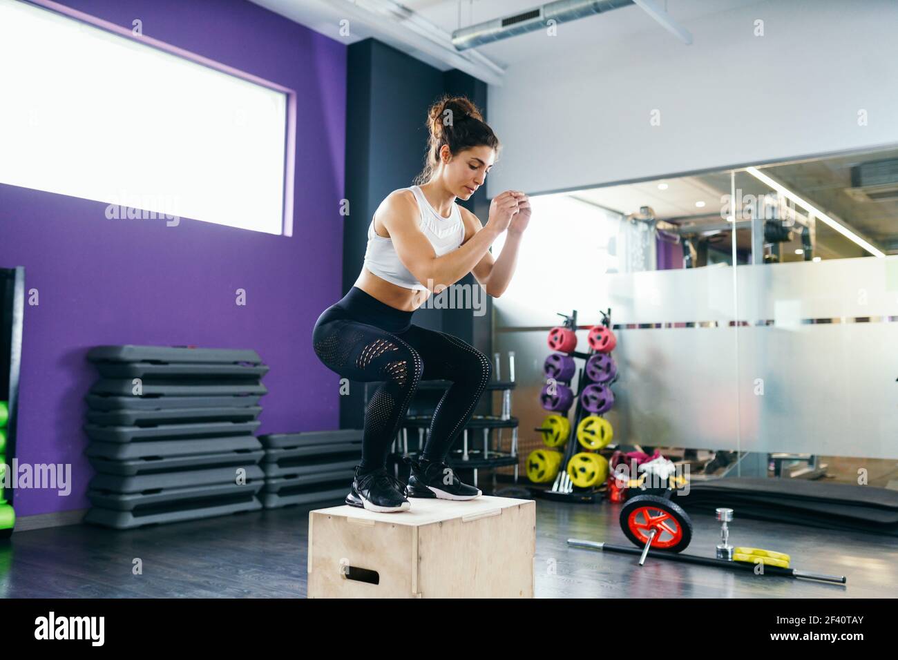 Donna atletica che fa squats sulla scatola come parte della procedura di esercitazione. Caucasica femmina facendo scatola salto allenamento in palestra.. Donna atletica che fa squats sulla scatola alla palestra Foto Stock