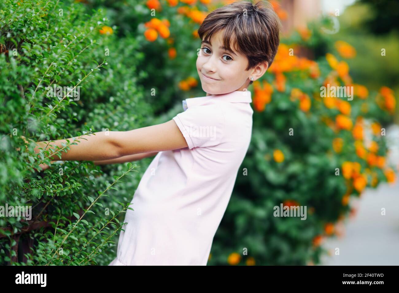 Bambina con capelli molto corti, divertirsi in un parco urbano con vestito rosa. Bambina, otto anni, che si diverte in un parco urbano. Foto Stock