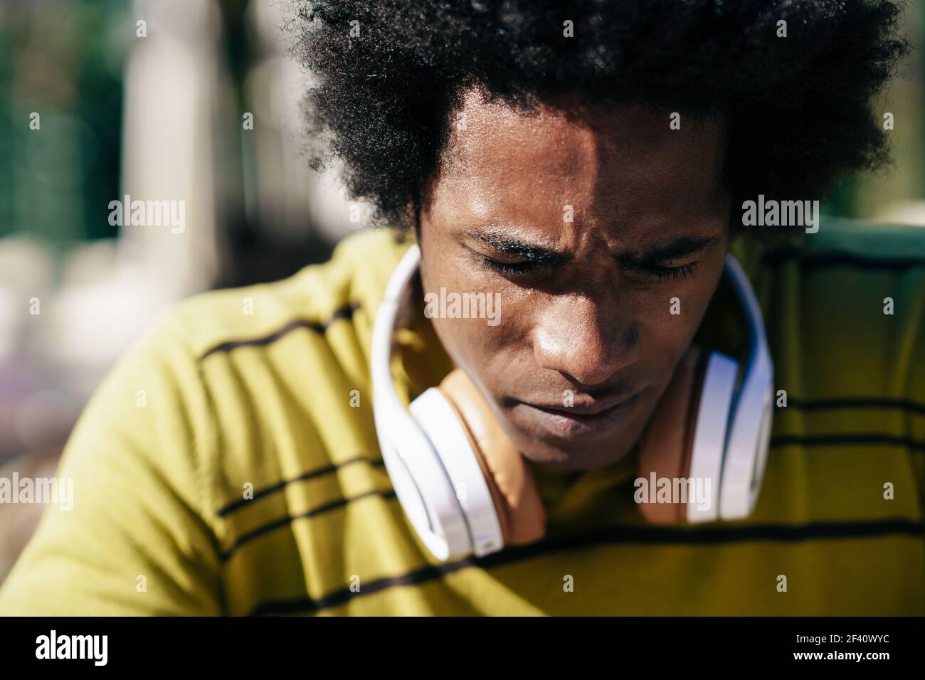 Primo piano ritratto di un uomo nero serio che guarda verso il basso. Ragazzo con le cuffie.. Primo piano ritratto di un uomo nero serio che guarda verso il basso. Foto Stock