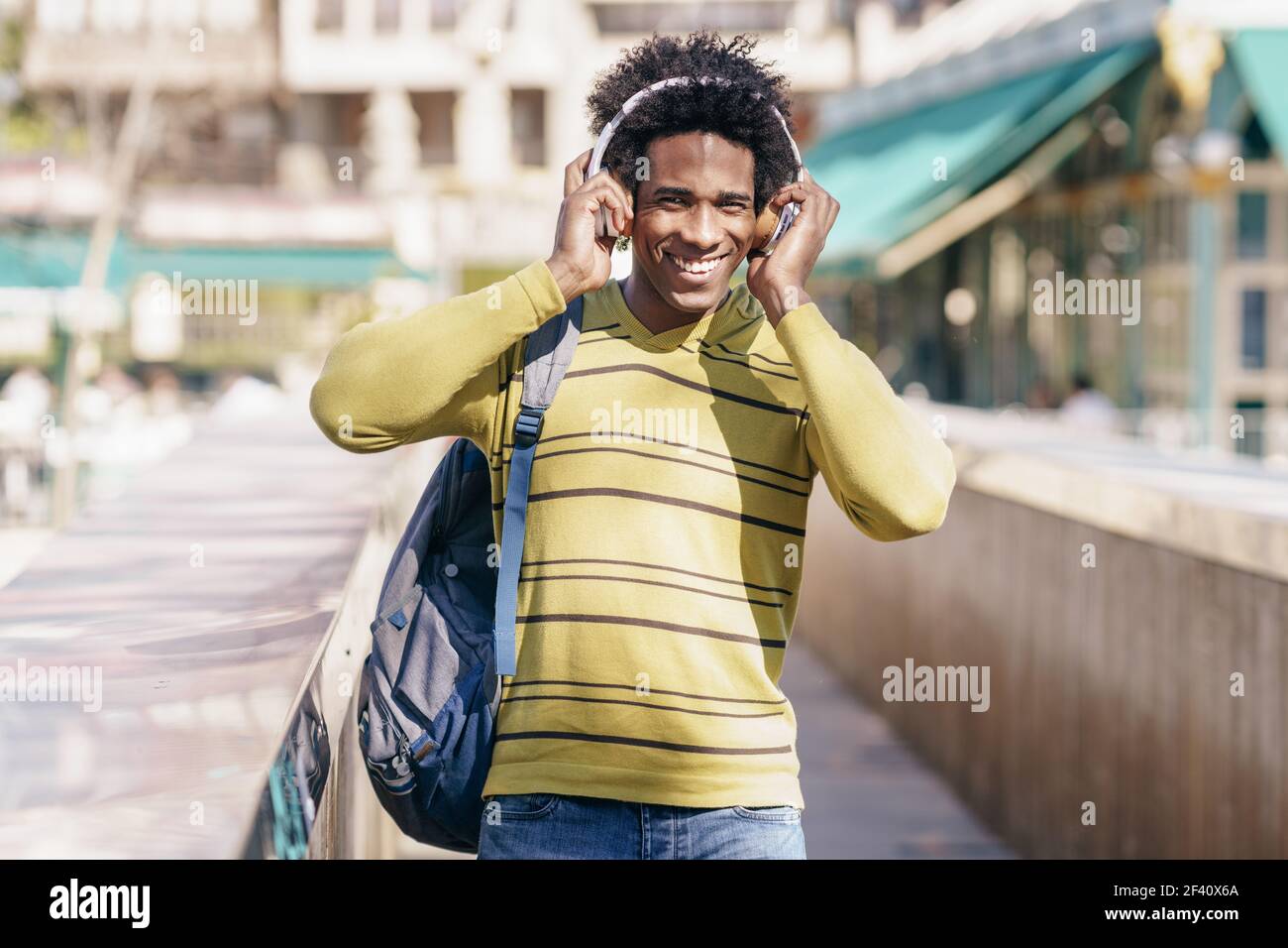 Uomo nero con capelli afro ascolto di musica con cuffie wireless visite turistiche a Granada, Andalusia, Spagna.. Uomo nero che ascolta la musica con le cuffie wireless per visitare Granada Foto Stock