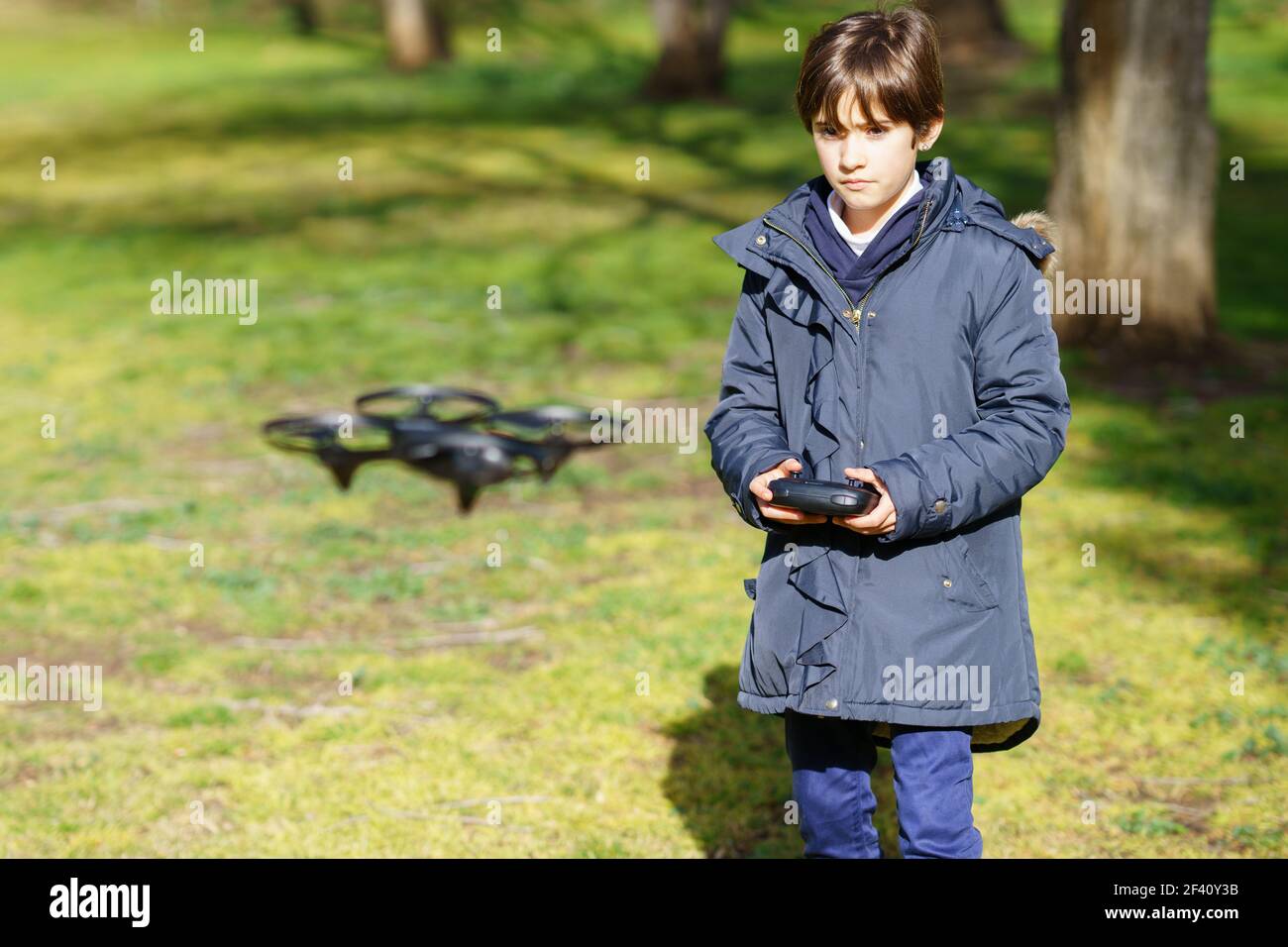 Bambina di nove anni che aziona il drone giocattolo che vola o che si sorvola con il telecomando in un parco. Bambina di nove anni che aziona il drone giocattolo che vola con il telecomando Foto Stock