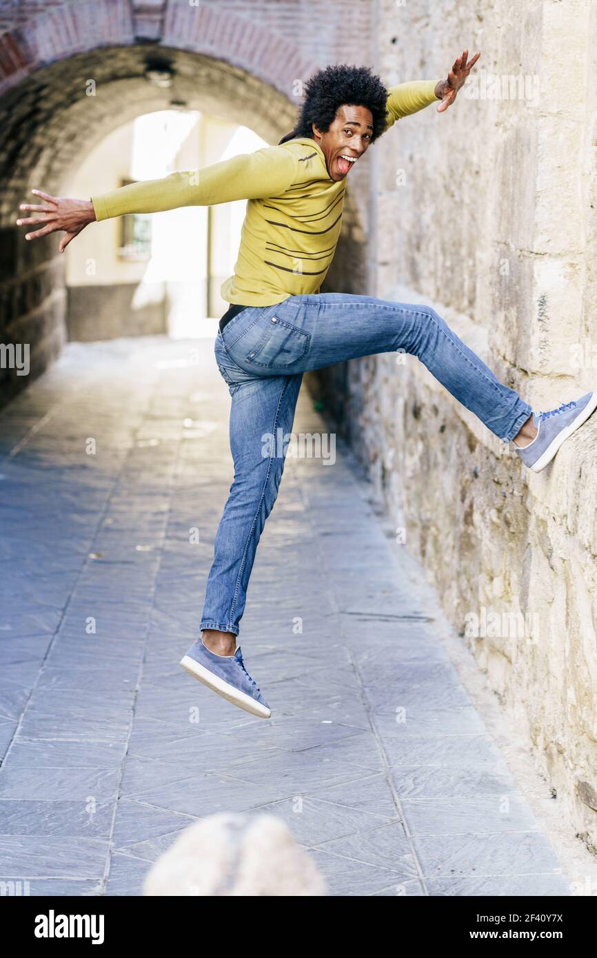 Uomo nero con capelli afro che saltano per la gioia per la strada. Uomo nero con capelli afro che saltano per gioia Foto Stock