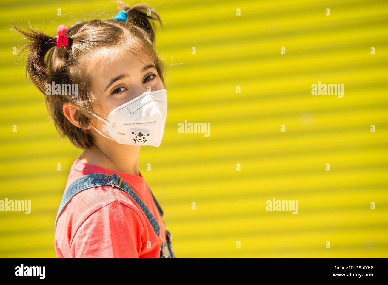 Happy Child ragazza che indossa una maschera di protezione contro il coronavirus durante la pandemia di Covid-19. Maschera KN95. Bambina che indossa una maschera di protezione contro il coronavirus durante la pandemia di Covid-19 Foto Stock