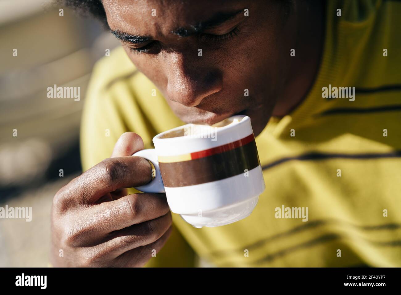 Cubano Black Man godendo di caffè in caffetteria mentre si siede al tavolo all'aperto durante il suo viaggio a Granada, Spagna. Black man gustando un caffè al caffè mentre si siede al tavolo all'aperto Foto Stock