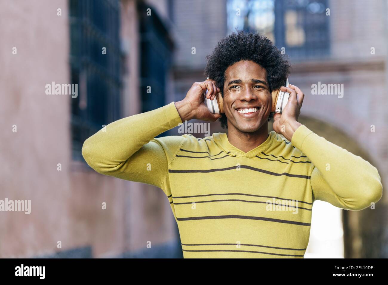 Uomo nero con capelli afro ascolto di musica con cuffie wireless visite turistiche a Granada, Andalusia, Spagna.. Uomo nero che ascolta la musica con le cuffie wireless per visitare Granada Foto Stock