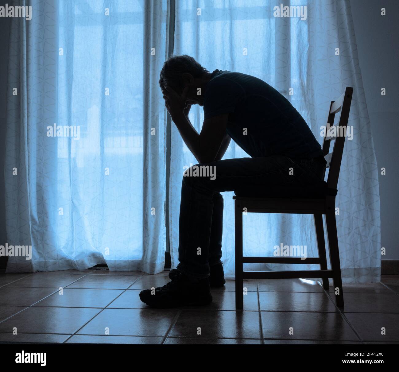 Uomo maturo (63 anni) con testa nelle mani vicino alla finestra. Depressione maschile, salute mentale, malattia mentale... concetto Foto Stock