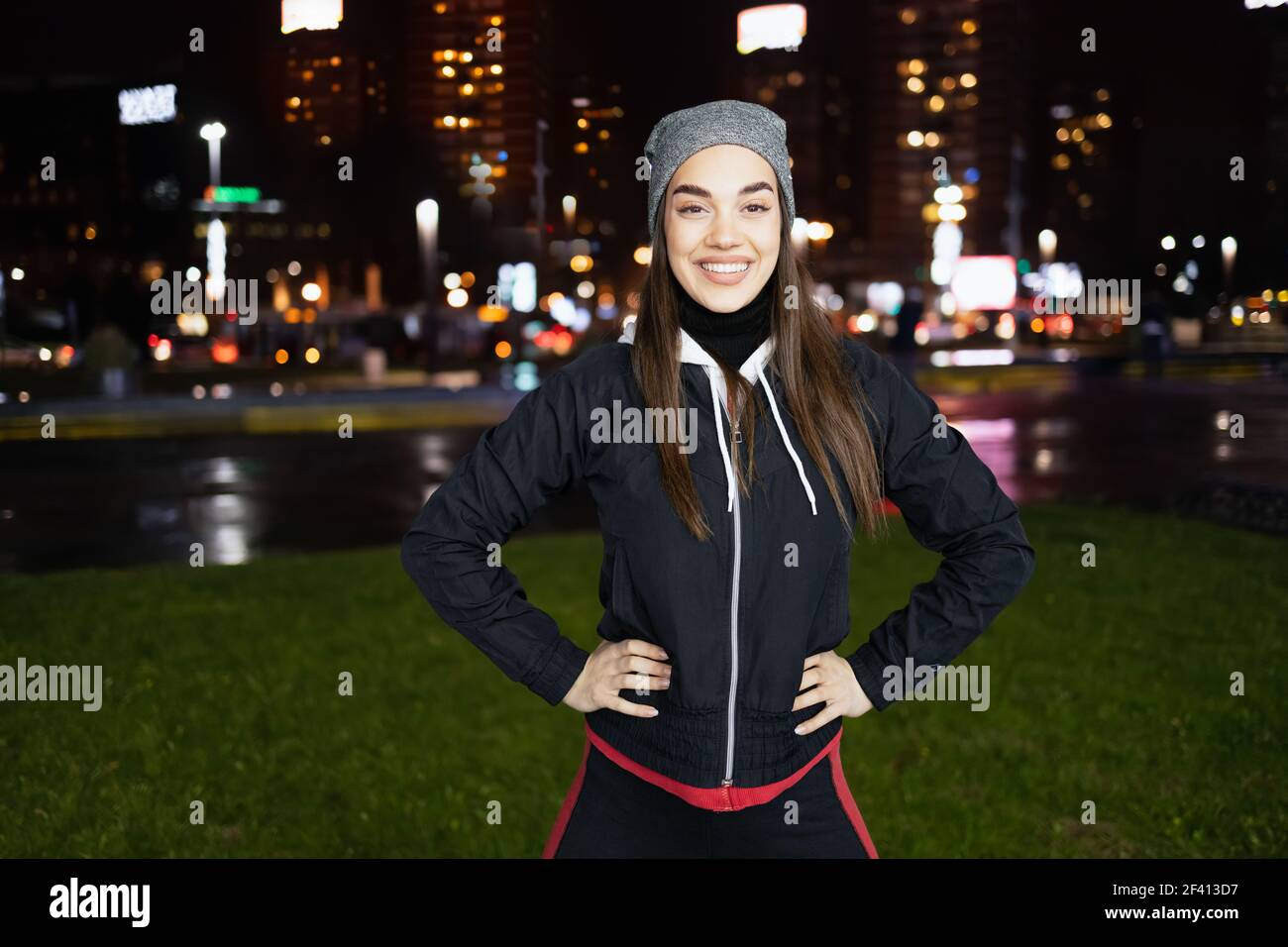 Il sorriso mentre si prepara per una corsa notturna intorno a. grande città Foto Stock