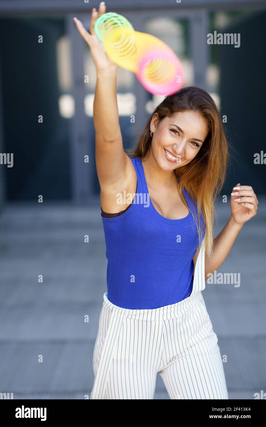 Ragazza che gioca con un colorato giocattolo primaverile su sfondo urbano. Ragazza che gioca con un colorato giocattolo primaverile all'aperto Foto Stock