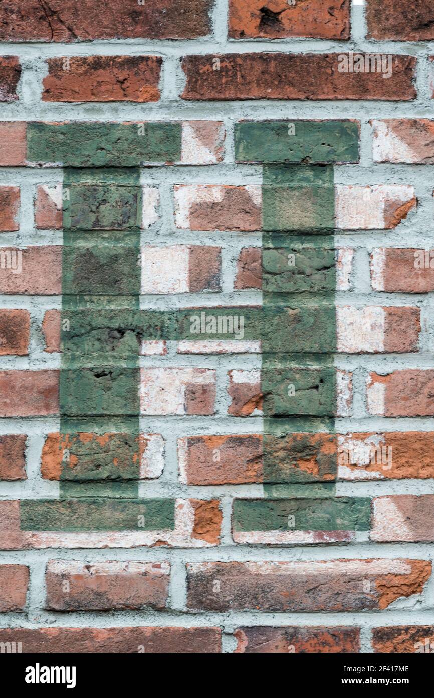 Una lettera verde H dipinta su una parete di mattoni rossi Foto Stock