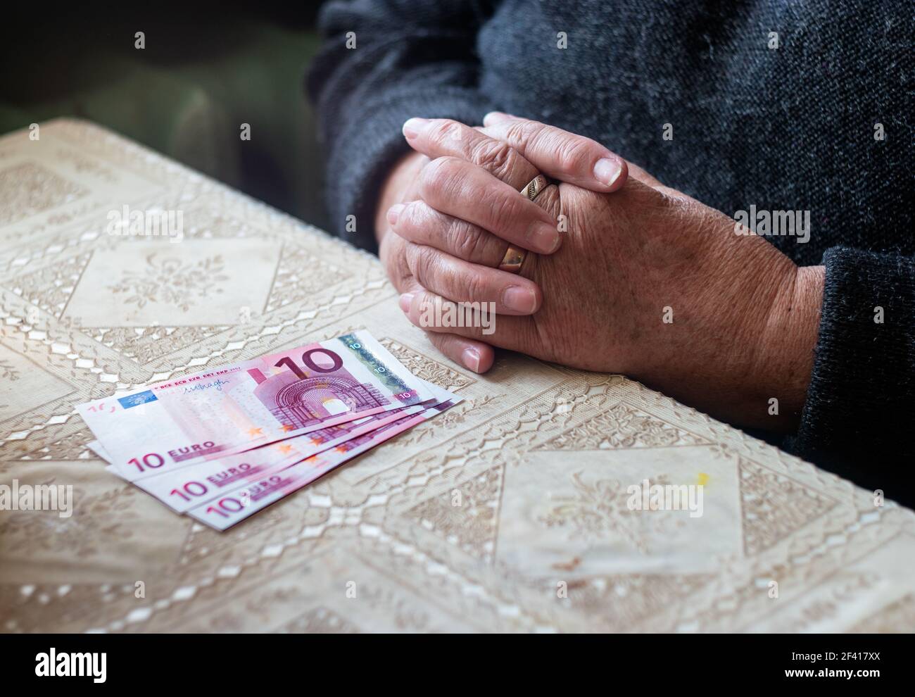 Donna anziana che piangono come spendere la sua pensione minima. Donna con alcune banconote in euro sul tavolo davanti a lei Foto Stock