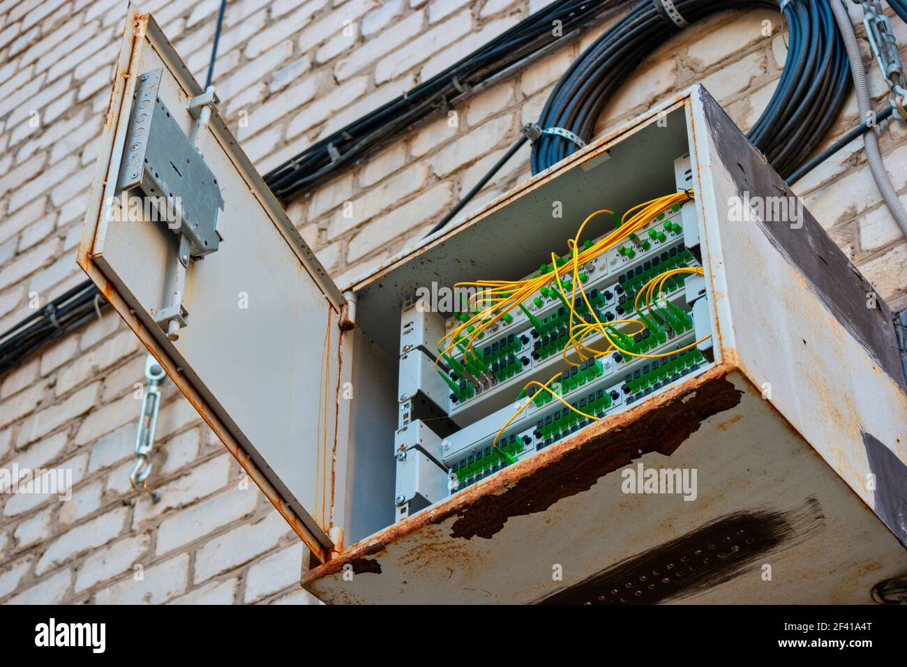 Pannello interruttori in fibra ottica sulla parete dell'edificio dell'appartamento con bobine di fili che si aggingono vicino. Pannello interruttori in fibra ottica sulla parete dell'edificio dell'appartamento con bobina di fili vicino Foto Stock