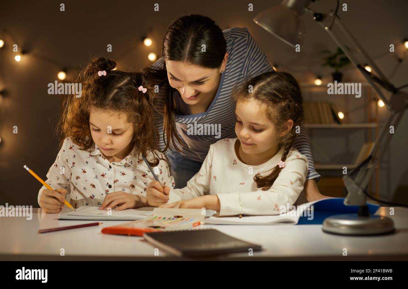 Ritratto di madre interessata all'attività serale delle figlie gemelle a. casa Foto Stock