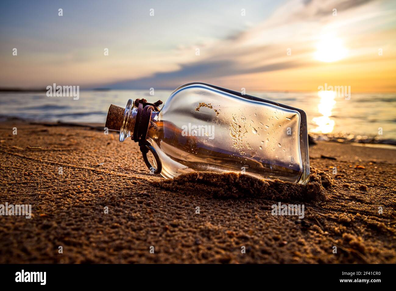 Messaggio in bottiglia contro il sole che tramonta verso il basso Foto Stock