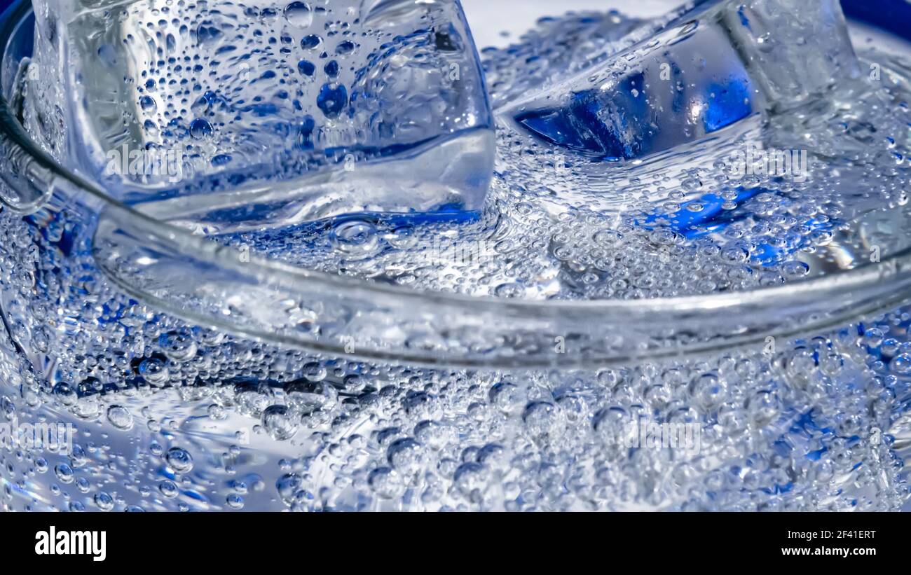 Bicchiere di acqua con ghiaccio su uno sfondo blu scuro Foto Stock