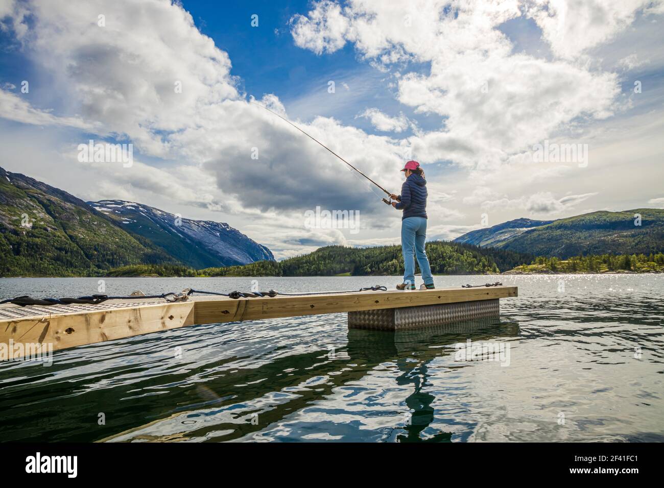 Donna che pesca sulla canna da pesca che gira in Norvegia. La pesca in Norvegia è un modo per abbracciare lo stile di vita locale. Innumerevoli laghi e fiumi e una costa estesa significa opportunità eccezionali... Foto Stock