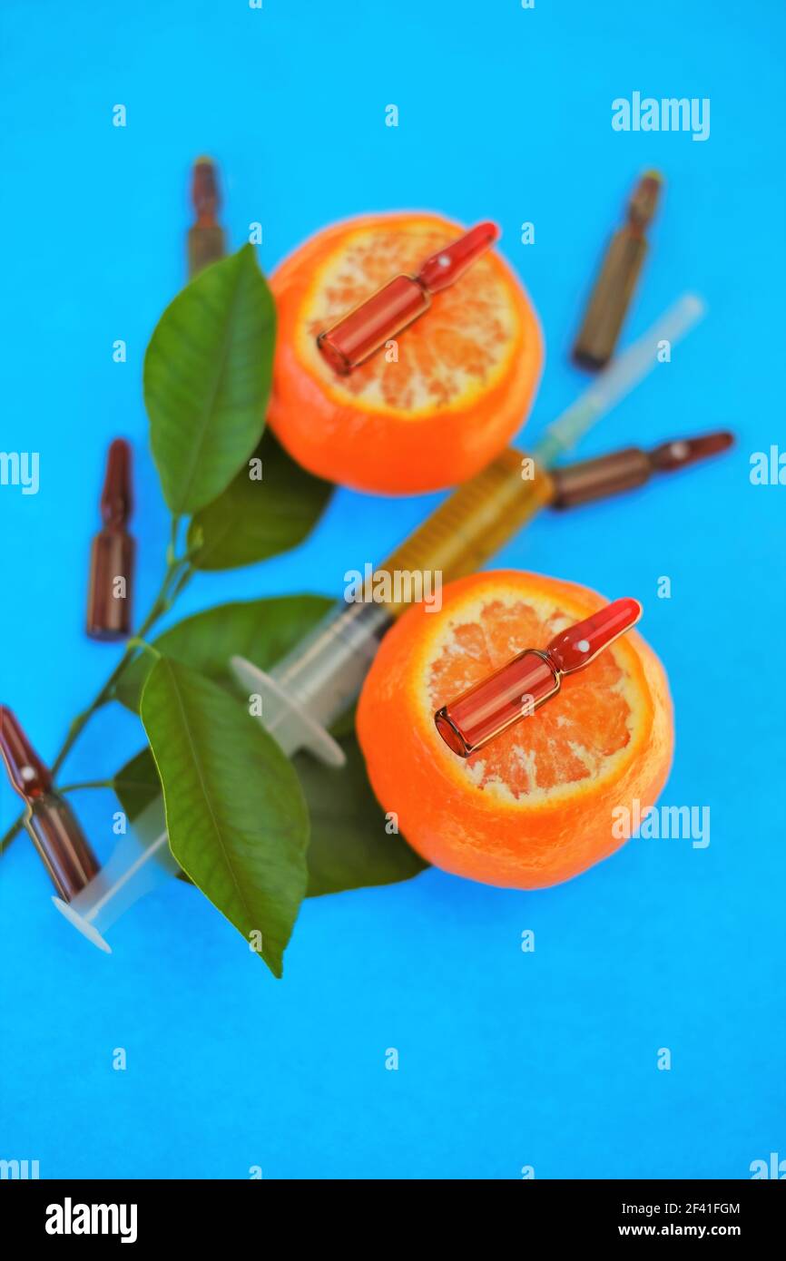 Siero di vitamina C. con vitamina C. ampolle di vetro da vicino e siringa con soluzione iniettabile su mandarino frutti con foglie di colore verde brillante su brillante Foto Stock