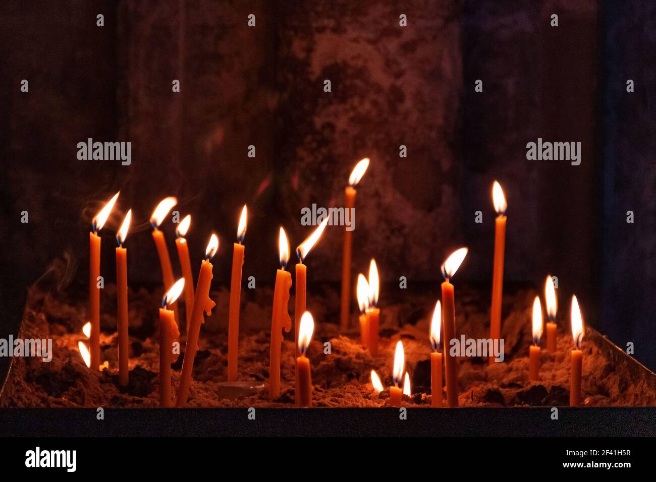 molte candele della chiesa di vari gradi di combustione, incastrate nella  sabbia nel fuoco selettivo. fuoco selettivo. che gocciola cera dalla candela  Foto stock - Alamy