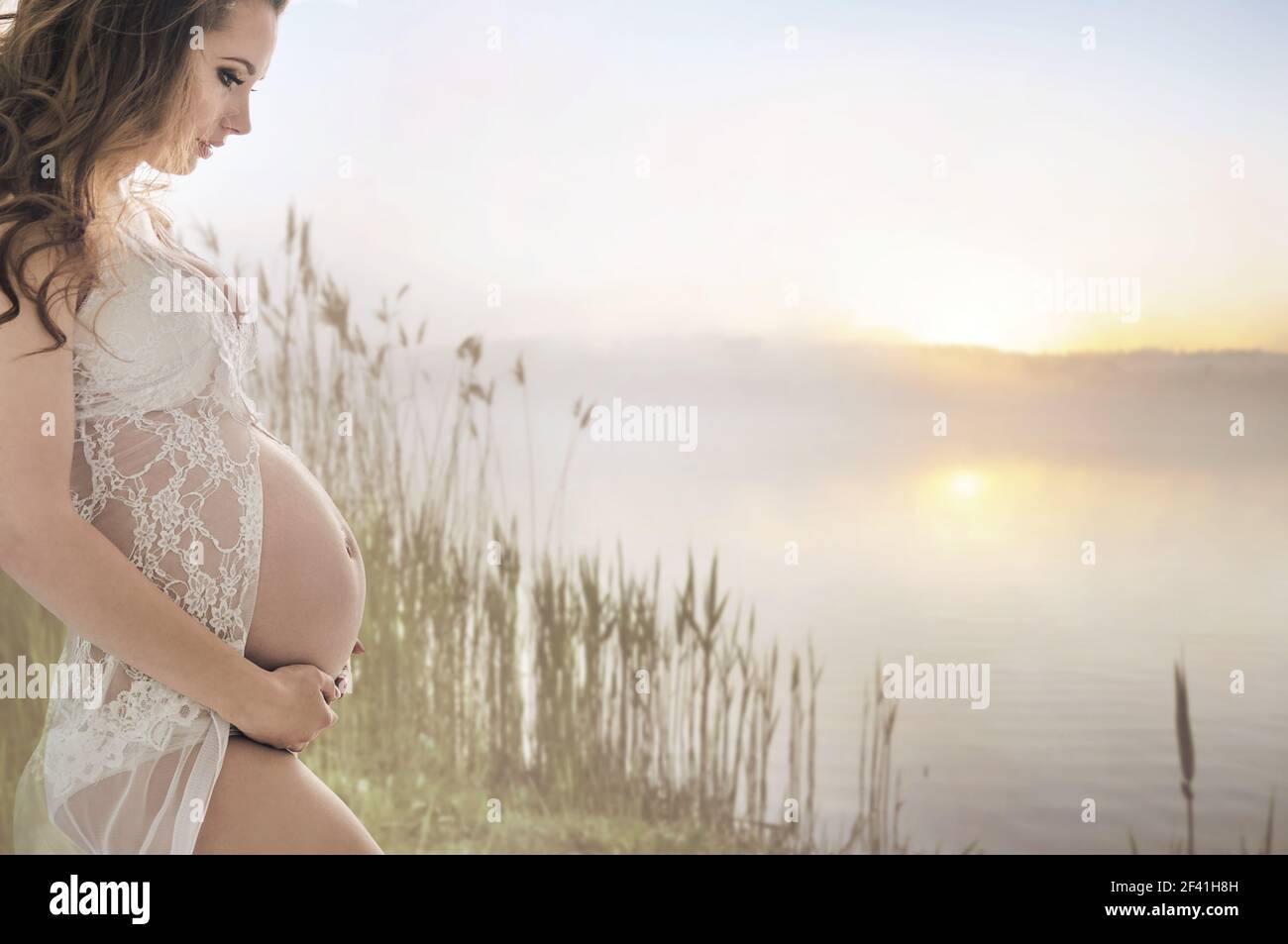 Calma la donna incinta rilassante in riva al lago Foto Stock