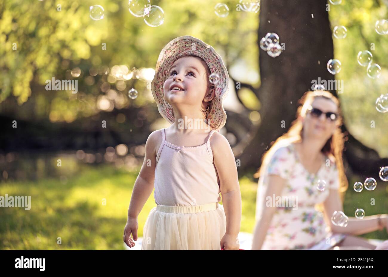 Madre e figlia guardando al luminoso bolle di sapone Foto Stock