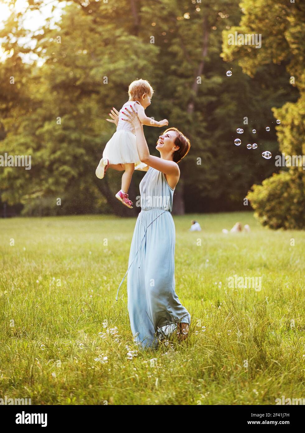 Felice giovane madre nel lanciare il suo bel bambino Foto Stock