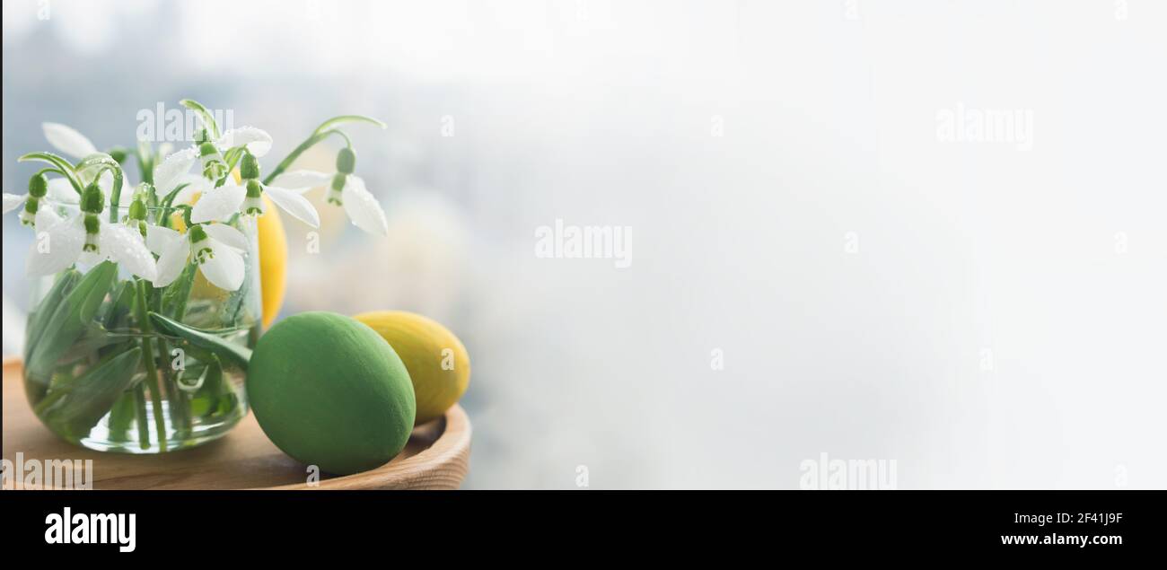 Primo piano su nevicate fresche in un vaso di vetro e uova di pasqua. Banner Foto Stock