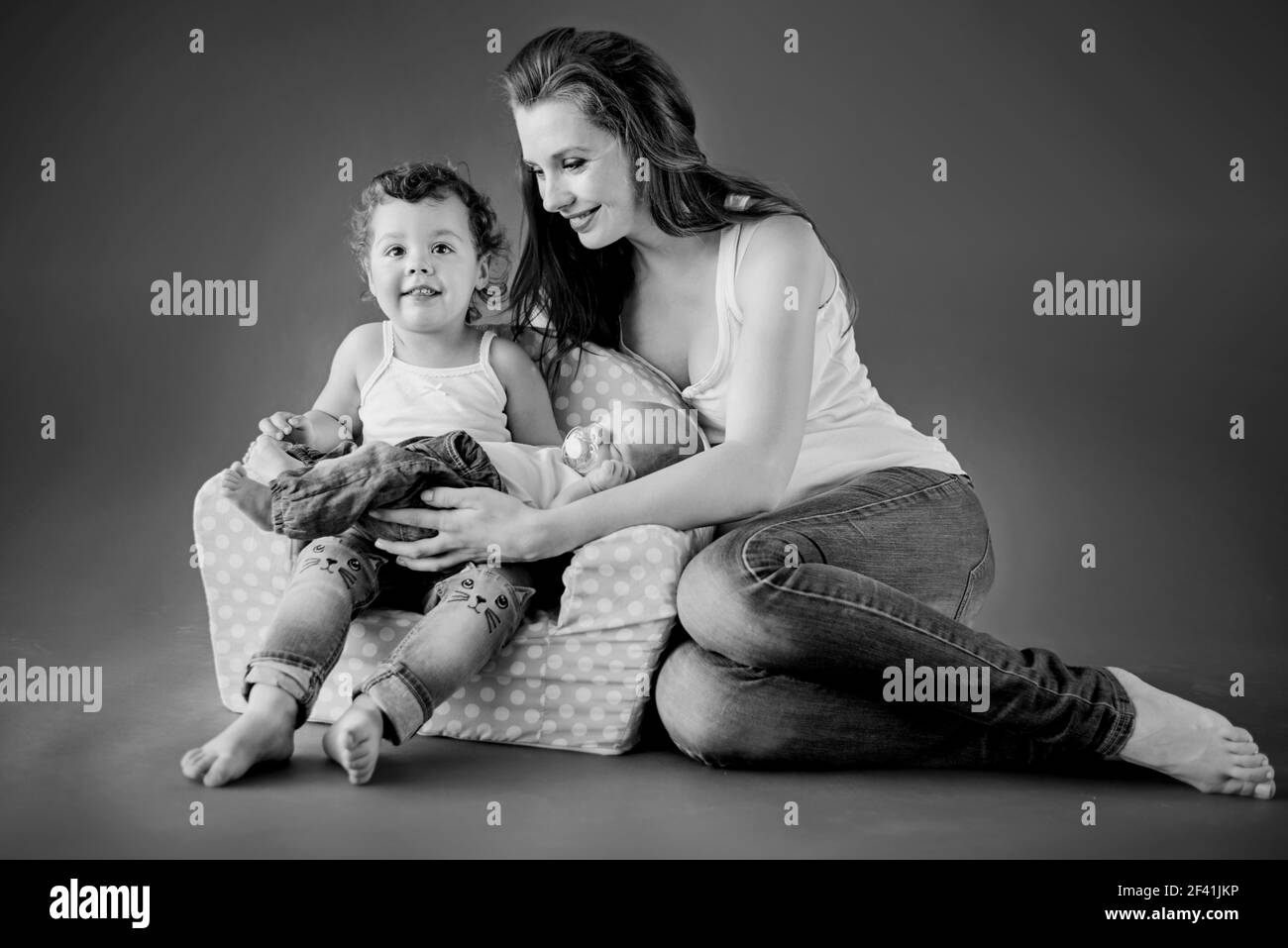 Madre giovane seduto sul pavimento con i suoi due bambini carino Foto Stock