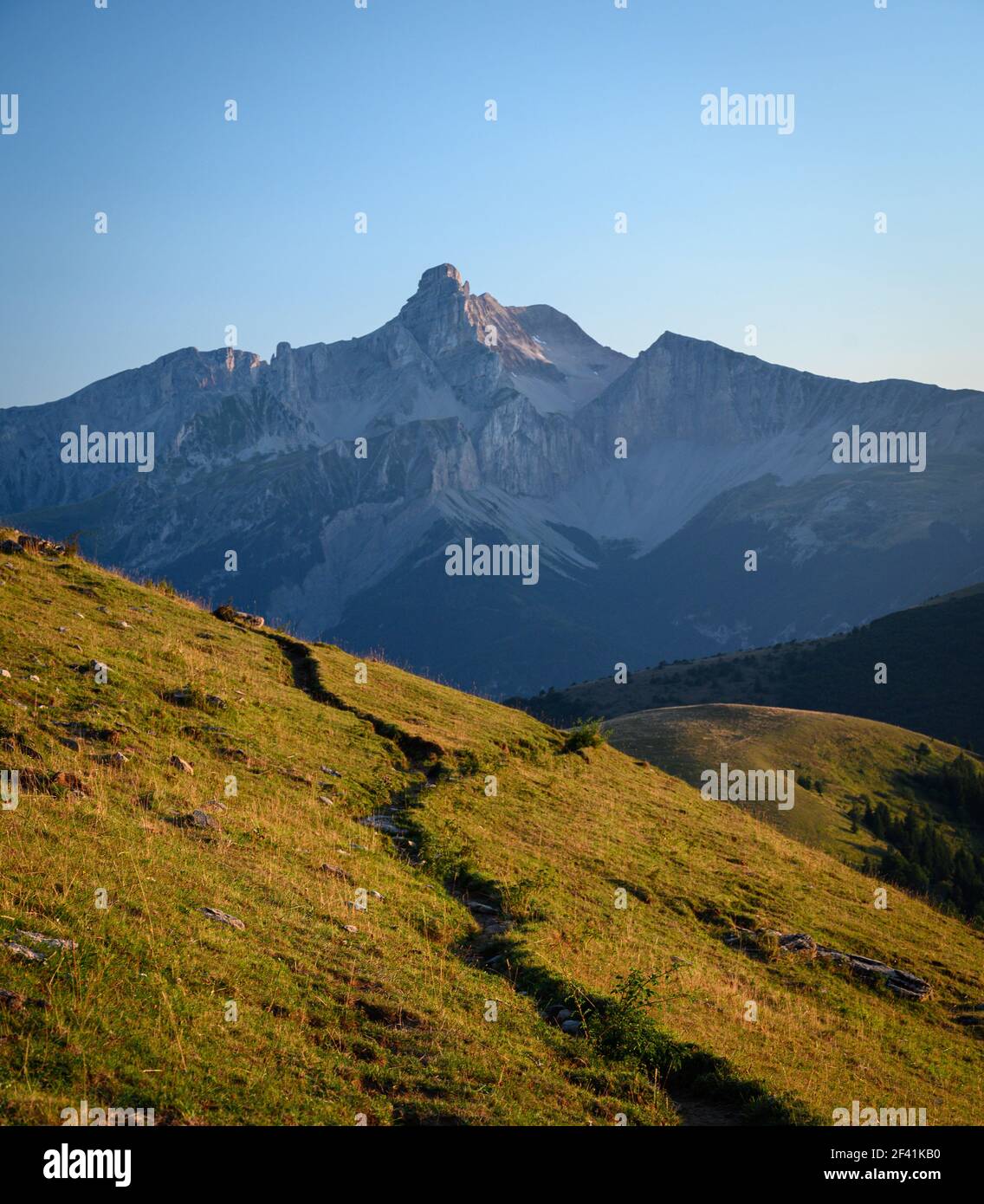 Percorso di montagna selvaggio con erba con montagna ripida in lo sfondo Foto Stock