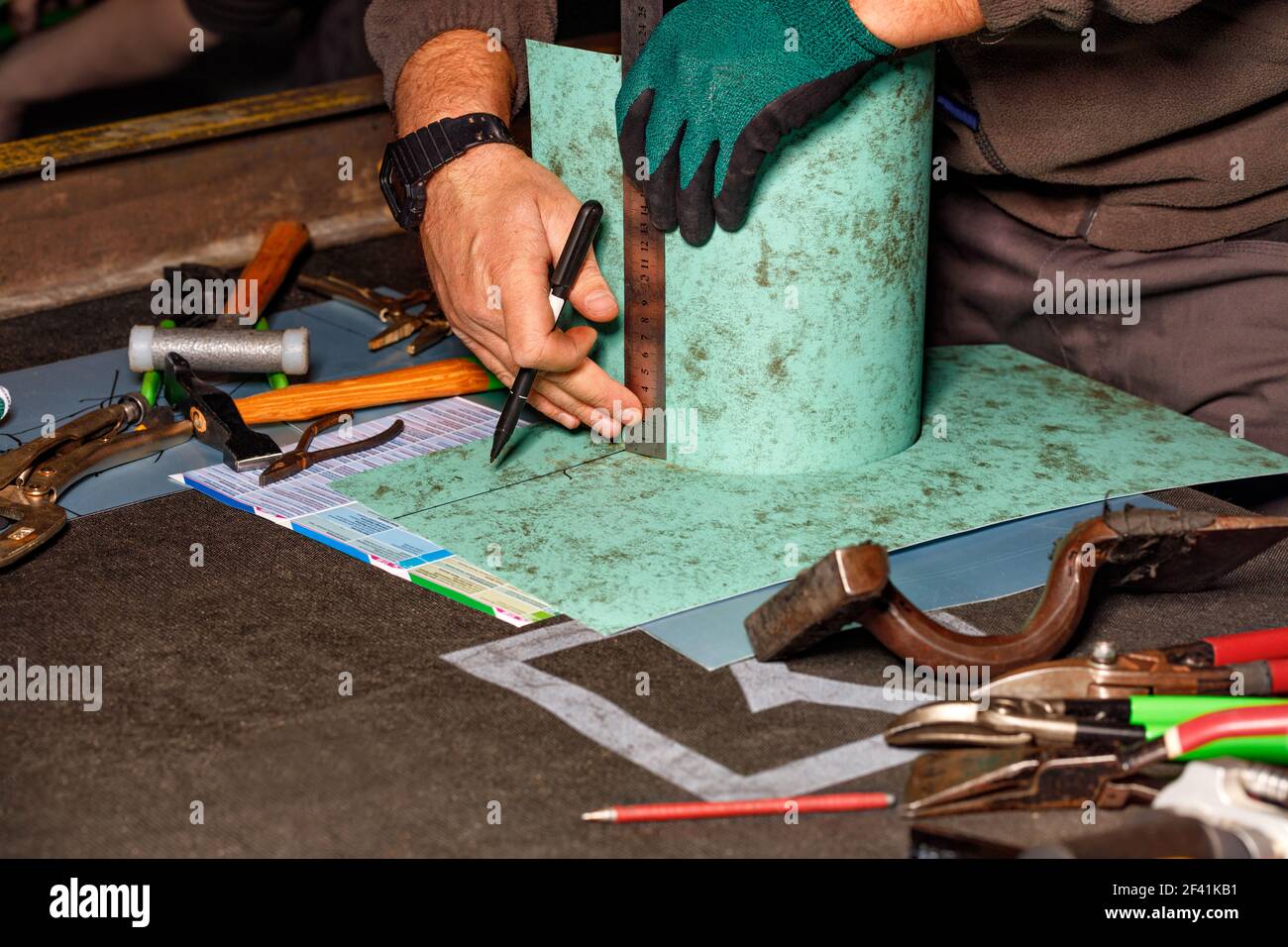 Il fabbro della sua officina contrassegna la dimensione richiesta sul pezzo con un pennarello e un righello. Foto Stock