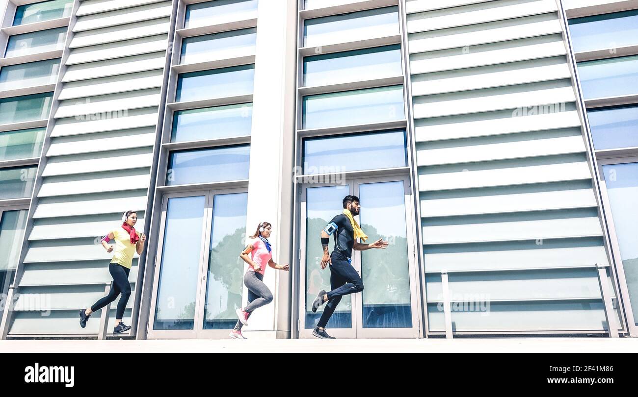 Giovani che corrono in una moderna area urbana - Fitness Girls Corsa con allenatore maschile in città - Sport concetto con amici gruppo jogging Foto Stock