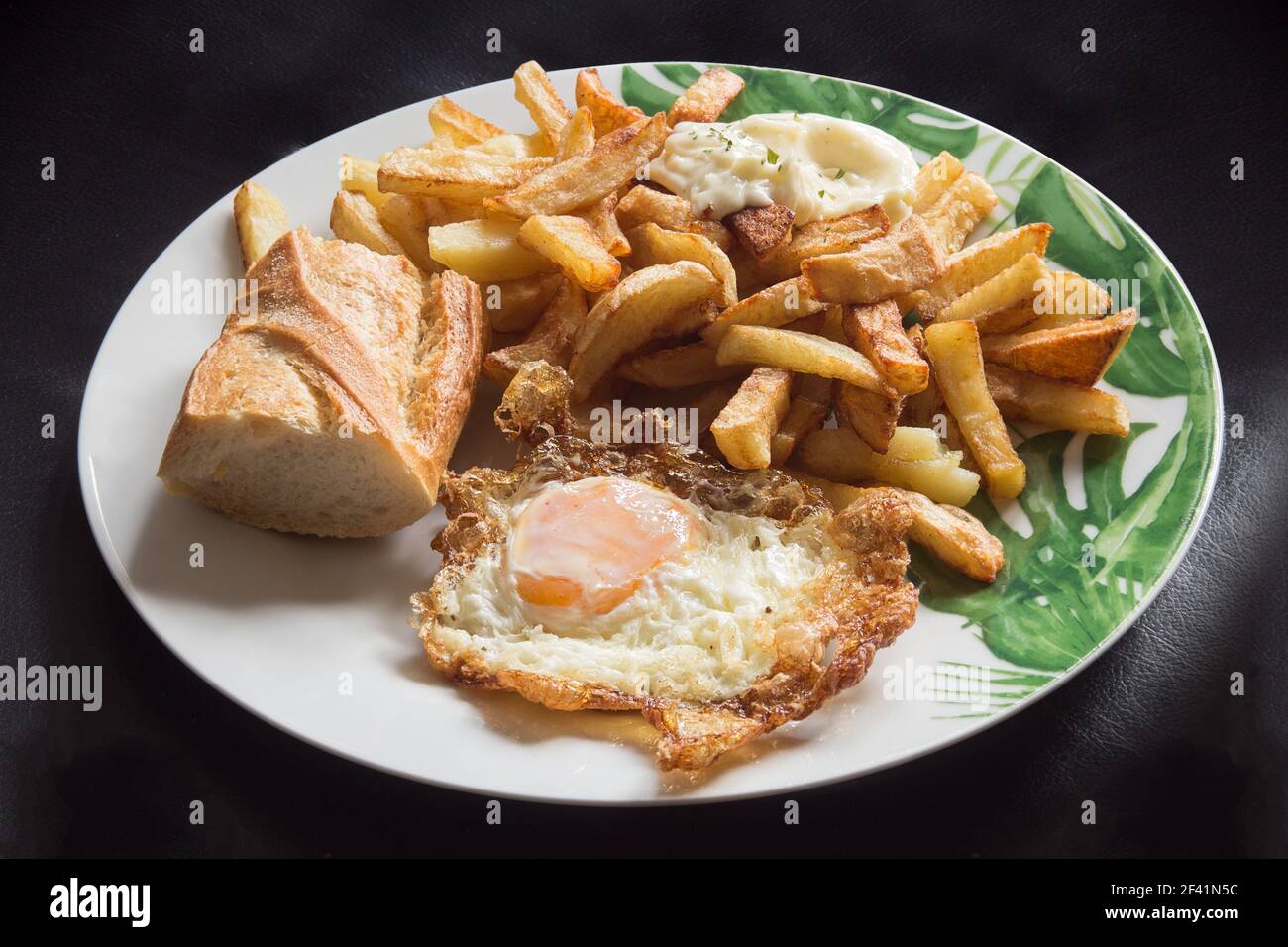 Presentazione dell'uovo fritto con pane e patatine su un piatto elegante. Cibo e ricette tradizionali. Foto Stock